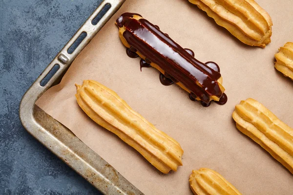 Eclairs o profiteroles con chocolate y crema batida preparación receta —  Fotos de Stock