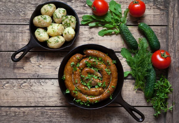 М'ясна ковбаса, запечена в чавунній сковороді з вареною картоплею — стокове фото