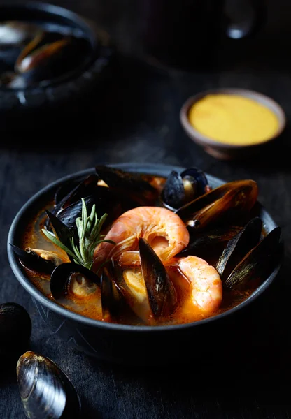 Sopa de peixe tradicional Marselha Bouillabaisse com camarões, mexilhões tomate, lagosta, lula. Fundo preto . — Fotografia de Stock