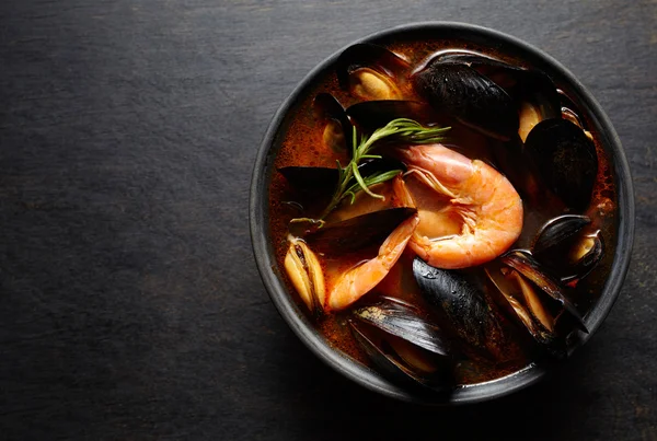 Sopa de peixe Bouillabaisse com camarões, mexilhões, tomate, lagosta e lula. Tradicional na França, Espanha. Fundo preto . — Fotografia de Stock