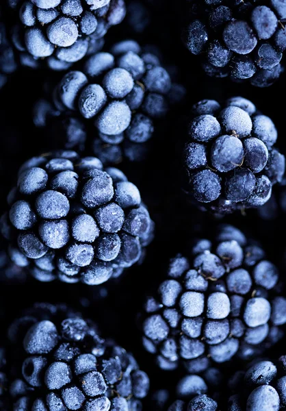 Nahsicht auf gefrorene Brombeerfrüchte auf einem Tisch aus schwarzem Stein. Lebensmittel-Hintergrund lizenzfreie Stockbilder