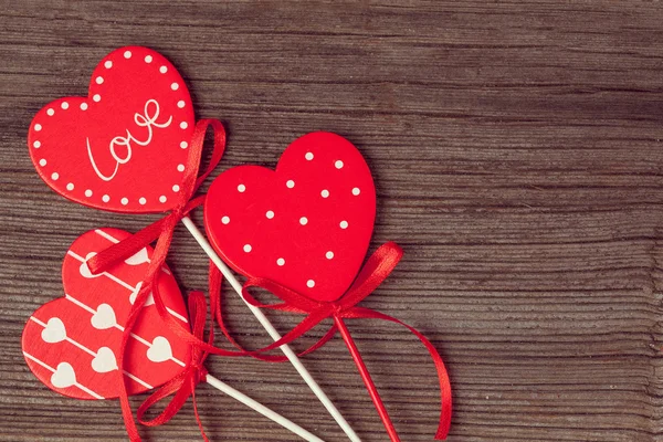 Variety of red hearts with ribbons on vintage wooden background — Stock Photo, Image