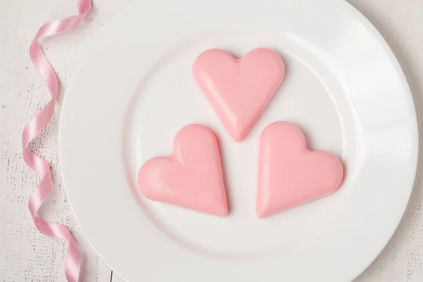 Pink heart-shaped jelly with ribbon on white dish — Stock Photo, Image