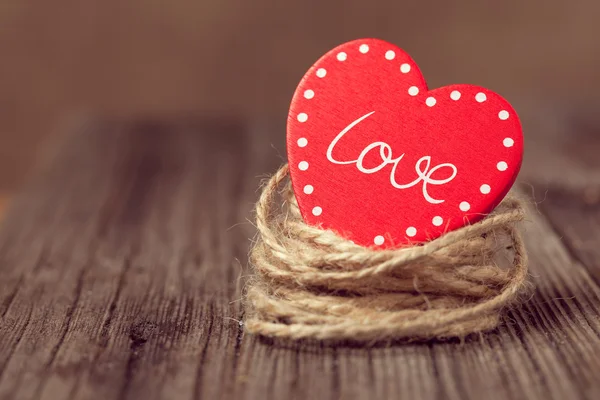 Red valentine's day heart with text in nest on wooden background — Stock Photo, Image