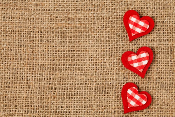 Retro Tekstil zemin üzerine kırmızı Sevgililer günü kalpleri — Stok fotoğraf