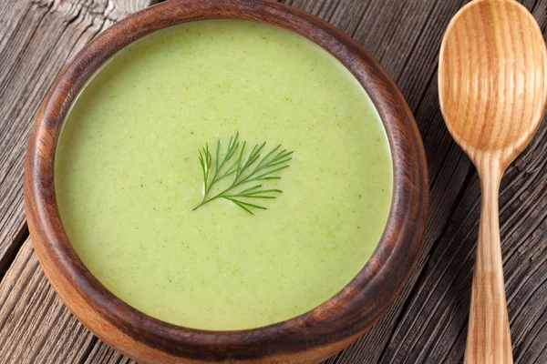 Зеленый кремовый суп брокколи в деревянной миске с ложкой — стоковое фото