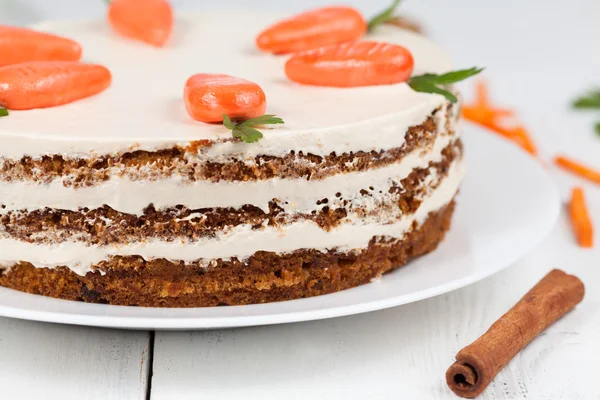 Gustosa torta di carote pasquali con panna e piccole carote su piatto bianco — Foto Stock