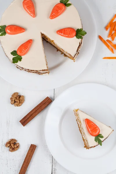 Leckere, in Scheiben geschnittene Osterkarotten-Biskuitkuchen mit Sahne und kleinen Karotten auf weißem Teller — Stockfoto