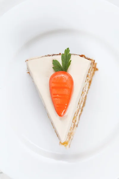 Pedaço de saboroso bolo de esponja de cenoura com creme de pastelaria e pequenas cenouras laranja em cima — Fotografia de Stock