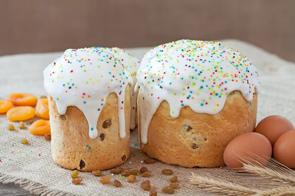 Traditional russian easter cake also called kulich with sugar icind, dried apricots and raisins on vintage textile — Stock Photo, Image