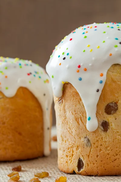 Homemade sweet bread traditional easter cake panettone also called kulich glazed with icing and raisins on vintage textile — Stock Photo, Image