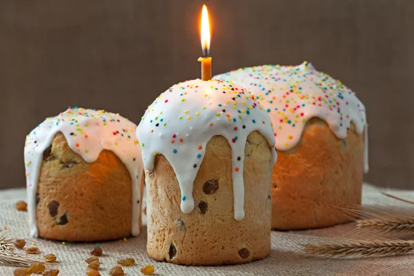 Традиційний саморобний український пиріг "Великодній торт" називається кулічем солодким хлібом з однією палаючою свічкою та глазур'ю на сільському текстилі — стокове фото