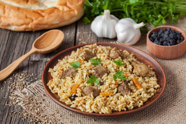 Tradicional pilaf comida uzbek. Arroz con carne, zanahoria y cebolla —  Fotos de Stock