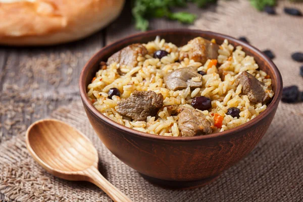 Traditional uzbek food called pilaf cooked with fried lamb meat, rice, carrot, onion and garlic — Stock Photo, Image