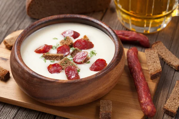 Пивний вершковий білий суп з сосисками та грінками на старовинній спині — стокове фото