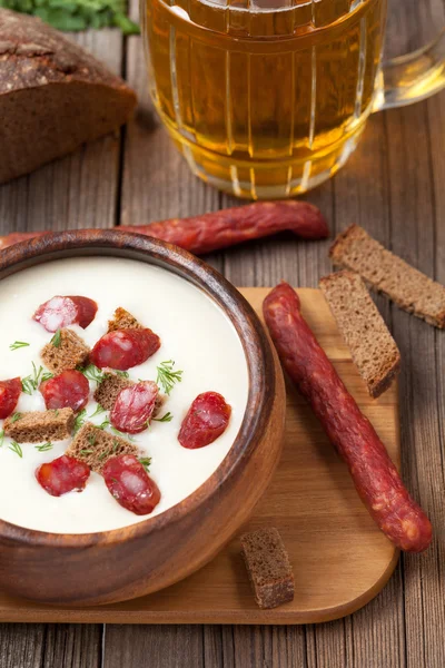 Cream beer soup with sausage in vintage wooden bowl and crouton — Stock Photo, Image