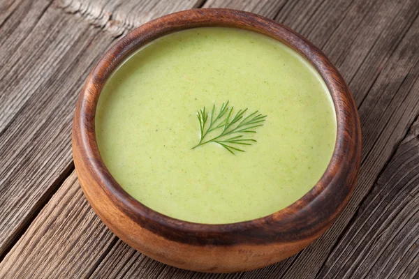 Чашка зеленого кремового супа с брокколи на ужин на винтажном столе — стоковое фото