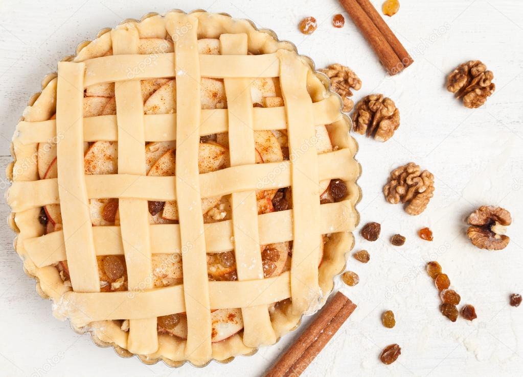 Homemade sweet pastry apple pie preparation. Raw tart with nuts, cinnamon and raisins
