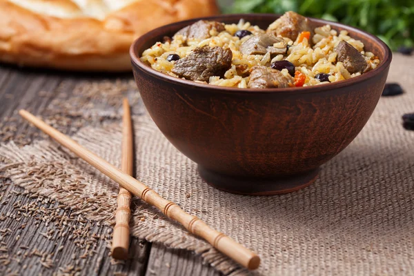 Παραδοσιακά υγιή ασιατικές εθνικές πικάντικο ρύζι πιλάφι τροφίμων μαγειρεμένα με τηγανητό κρέας, κρεμμύδι, καρότο και το σκόρδο. Ρουστίκ στυλ — Φωτογραφία Αρχείου