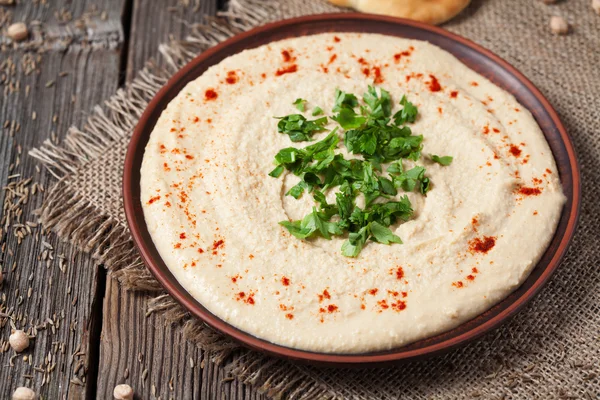 Hummus cremoso hebrew grão-de-bico comida na tigela com azeite e páprica — Fotografia de Stock