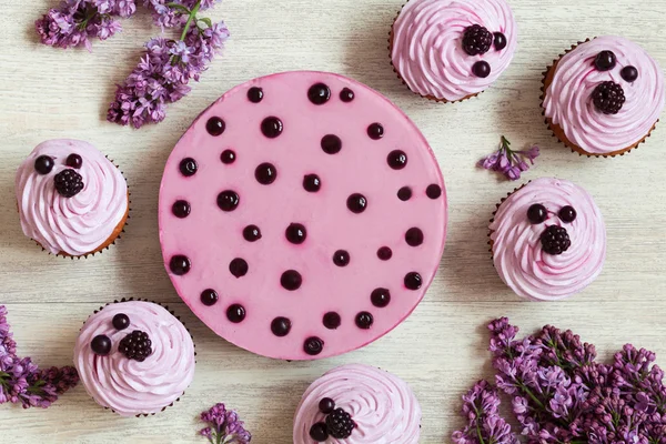 Cupcakes und Beerenmousse-Dessert mit frischen Beeren, Flieder auf weißem Küchentisch Hintergrund dekoriert. natürliches Licht, rustikaler Stil. — Stockfoto