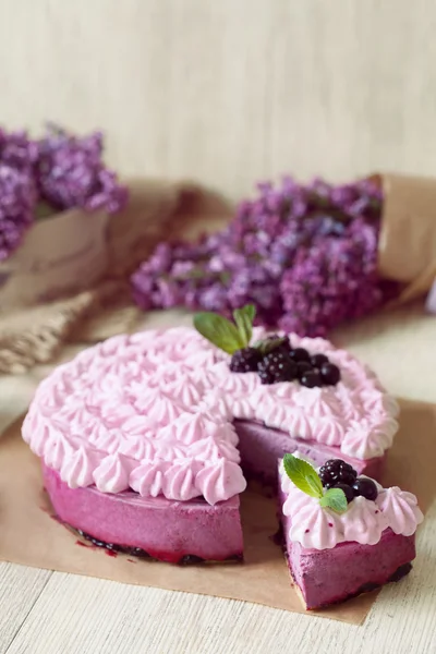 Berry purple mousse cake. Delicious homemade baked sweet decorated with blackberry and whipped cream. Rustic style, natural light.