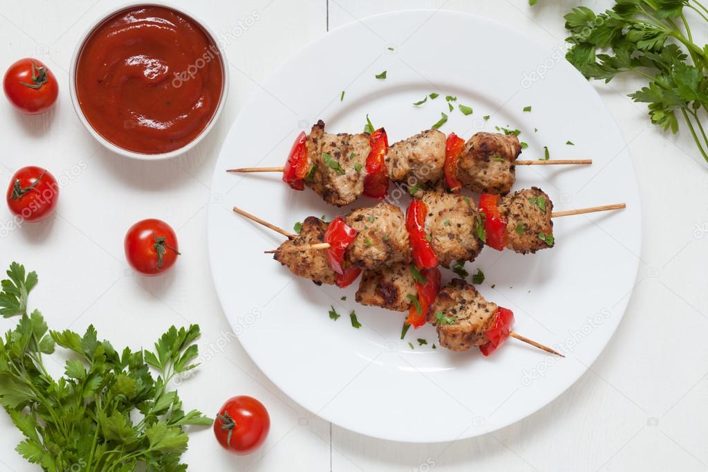 Grilled chiken kebab skewer barbecue meat with pepper and sauce on white dish.