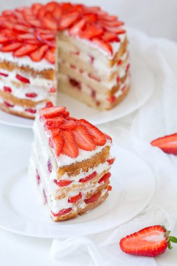 Lezzetli geleneksel rustik yaz Çilekli pasta tatlı tatlı yiyecek ile dilim krem ve kırmızı taze çilek beyaz mutfak masa arka plan üzerine şanti.