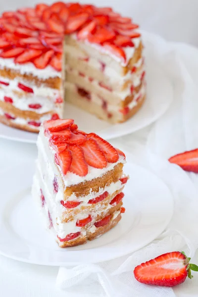 Slice of delicious traditional rustic summer strawberry cake sweet dessert food with whipped cream and red fresh strawberries on white kitchen table background — Stock Photo, Image