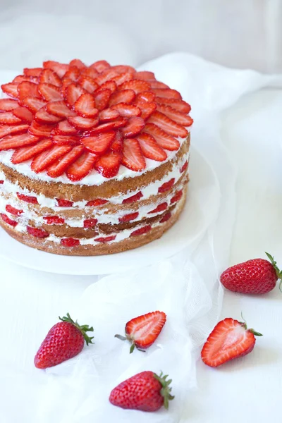 Homemade delicious strawberry sponge cake decorated with fresh strawberries on white kitchen table background — Stock Photo, Image