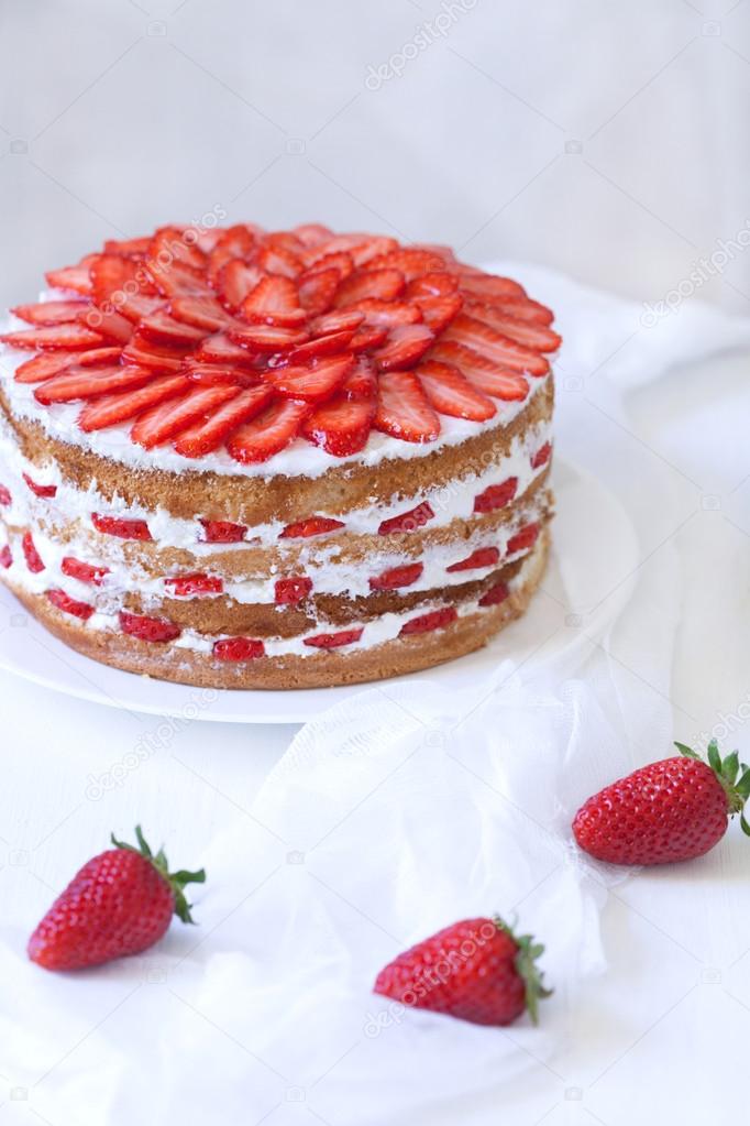 Gourmet traditional strawberry sponge cake weet dessert food served with sweet strawberries on white kitchen table