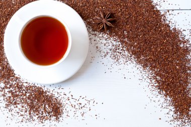 White cup of tasty traditional organic red rooibos tea with star anise clipart