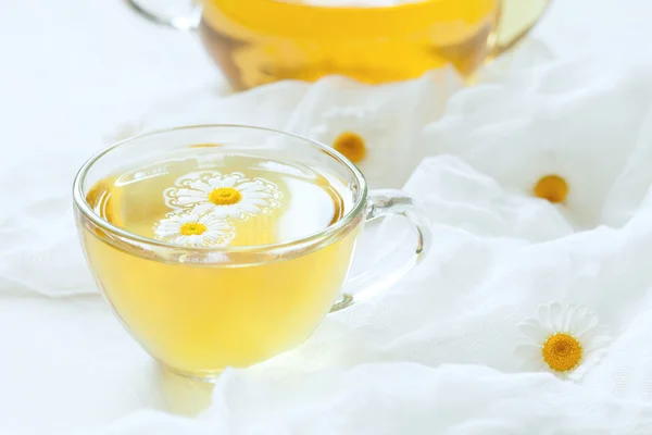 Chá de camomila medicina alternativa natural aromaterapia bebida relaxante em copo transparente com flores em fundo mesa de cozinha rústica branca — Fotografia de Stock