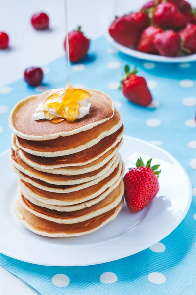 Pfannkuchen traditionelle hausgemachte amerikanische Dessert in weißer Schale mit Butter und Erdbeere gestapelt. Honig darüber gießen. — Stockfoto
