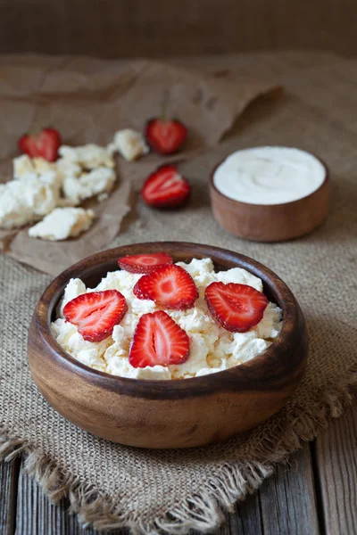 Homemade cottage cheese natural organic breakfast with strawberry and sour cream in wooden dish on rustic kitchen table — Stock Photo, Image