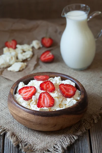 Cottage cheese healthy organic nutrition breakfast with milk and strawberry in rustic wooden dish on vintage kitchen table background — Stock Photo, Image