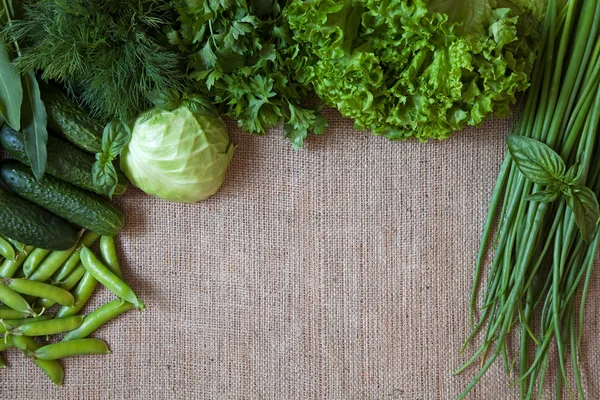 Marco de composición de verduras verdes sobre fondo de saco rústico. Guisantes, col, pepino, albahaca, eneldo, cebolla , —  Fotos de Stock