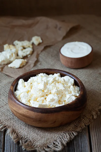 Traditional homemade cottage cheese with sour cream in rustic wooden dish on vintage kitchen table background — Stock Photo, Image