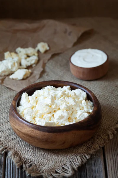 Queso cottage tradicional casero con crema agria en plato de madera rústica sobre fondo de mesa de cocina vintage — Foto de Stock