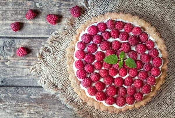 Homemade traditional sweet raspberry tart pie with cream and mint on vintage wooden table background — Stock fotografie