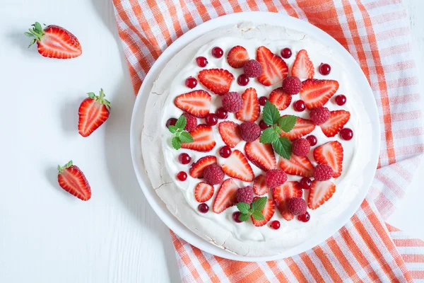 Tradiční Nový Zéland dezert Pavlova dort se šlehačkou crean ovoce a bezi na pozadí bílých rustikální stůl — Stock fotografie