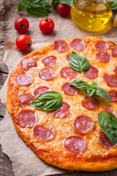 Pyszne domowe włoska pepperoni pizza z salami, mozzarella, pomidory i czosnek. Tradycyjne dania kuchni śródziemnomorskiej na tle starodawny stół drewniany. — Zdjęcie stockowe