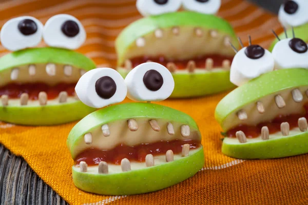 Homemade halloween scary food monsters natural vegetarian snack. Celebration party decoration recipe. Cute apple mouth with eyes and sunflower seeds tooth on vintage wooden table background — Stock Photo, Image