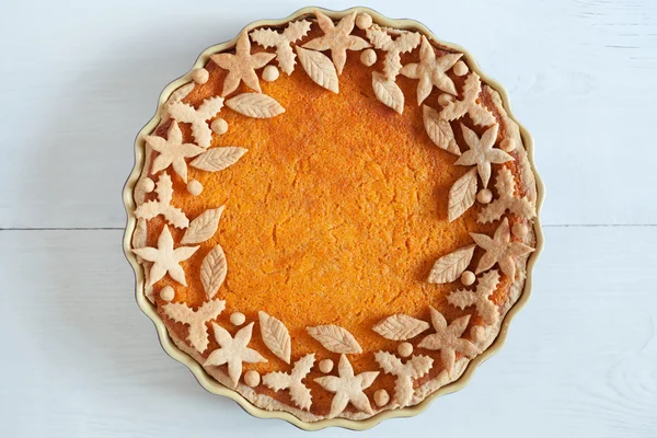 Homemade delicious pumpkin tart pie with decorations on top. Healthy organic nutrition pastry. Traditional autumn thanksgiving or halloween holiday food. White wooden background. — Stockfoto