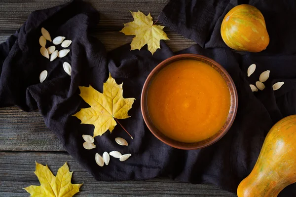 Deliziosa zuppa di zucca giorno di Halloween o di ringraziamento ricetta alimentare biologica naturale. Tessuto scuro su sfondo tavolo in legno vintage . — Foto Stock