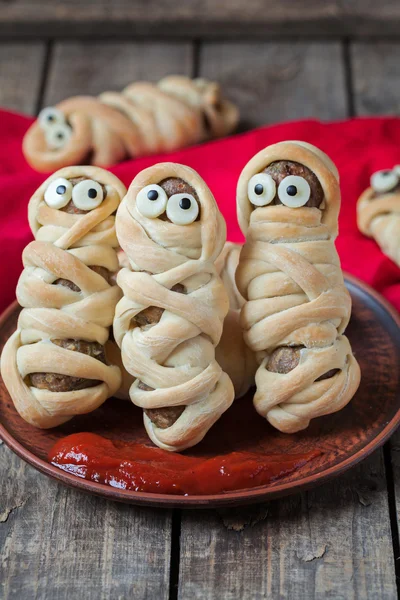 Meatball sausage mummies wrapped with dough. Scary halloween decoration food on vintage wooden background. — 스톡 사진
