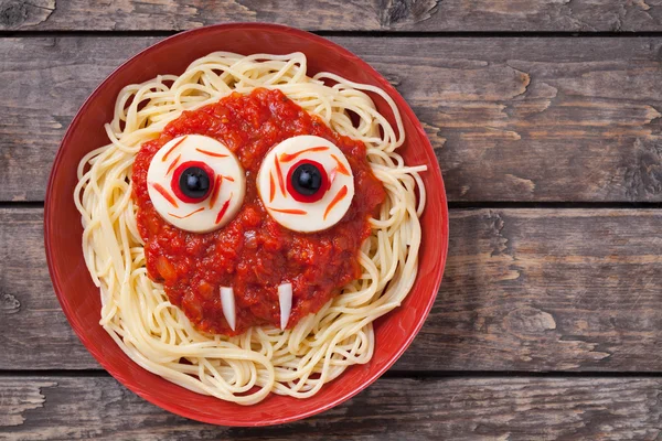 Scary halloween food pasta vampire monster face with big eyes and fangs for celebration party decoration. Vintage wooden background — Stock Photo, Image