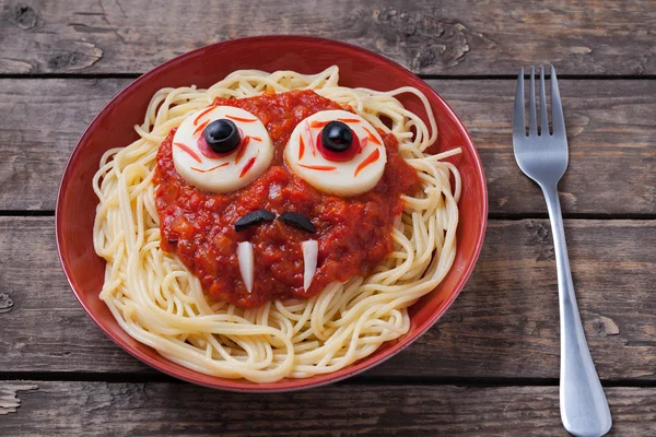 Cara de espaguete de Halloween com grandes presas oculares e bigodes em prato de macarrão, para festa de celebração na mesa vintage Fotografia De Stock