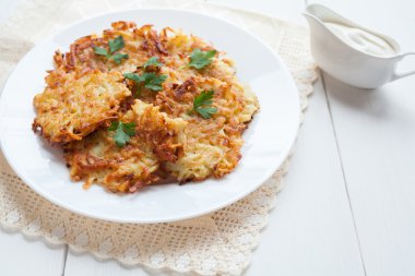 Patates pancaces ya da latke geleneksel Hanuka kutlaması gıda ile ekşi krema beyaz rustik arka planda. Vejetaryen organik yemek.