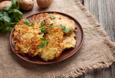 Geleneksel patates gözlemesi ya da latke ev yapımı Yahudi yemegi Hanuka kutlaması tarifi. Ev yapımı organik vegan yemek kil çanağı vintage ahşap zemin üzerine.